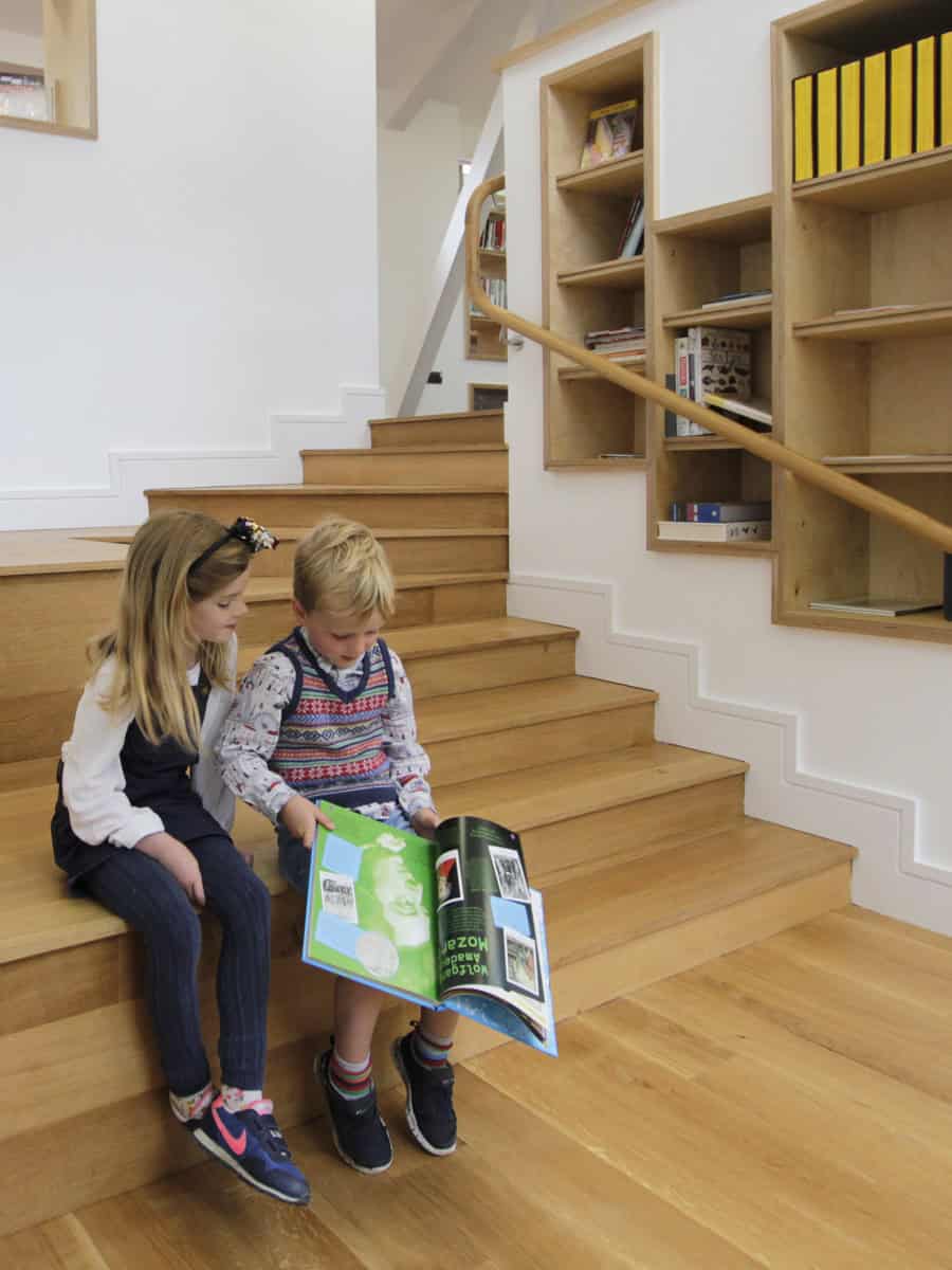 Beaudesert Park School Library with children reading on oak stepped seating beside timber shelves